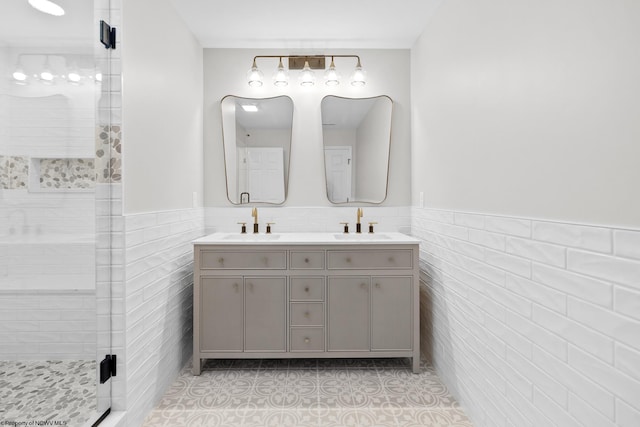 bathroom with a wainscoted wall, a shower stall, tile walls, and a sink