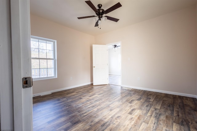 spare room with dark wood-style floors, baseboards, and a ceiling fan