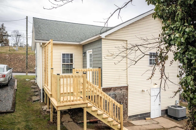 back of house featuring a deck, central AC, and roof with shingles