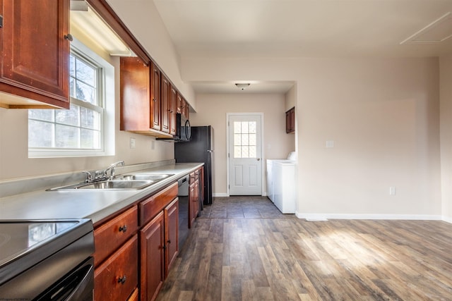 kitchen with a sink, washer / dryer, light countertops, and dark wood finished floors