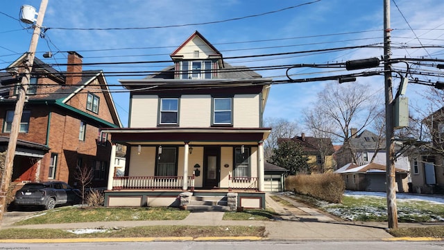 american foursquare style home with a porch and a detached garage