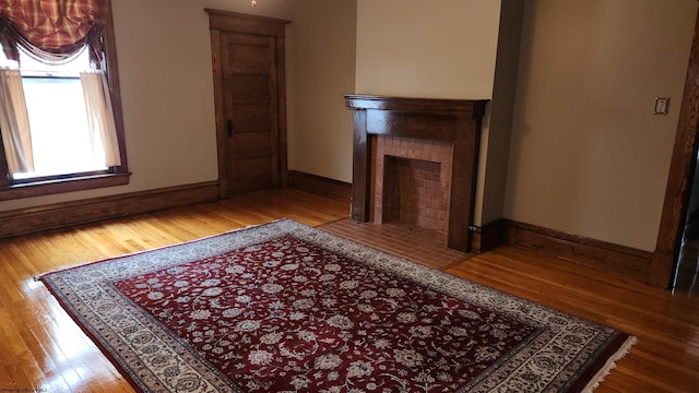 unfurnished living room with a fireplace, baseboards, and wood finished floors