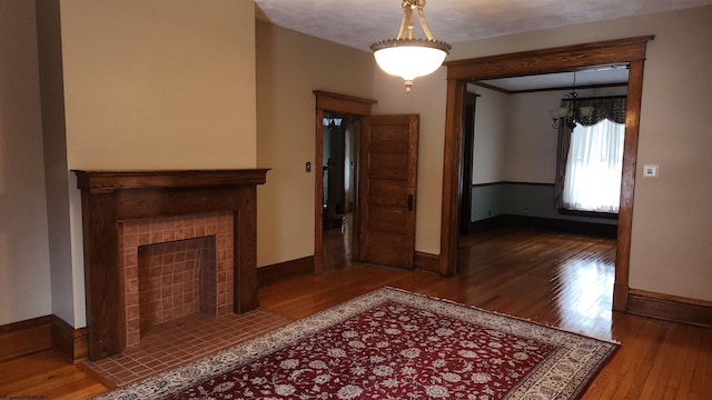 unfurnished living room featuring wood-type flooring, a fireplace, and baseboards