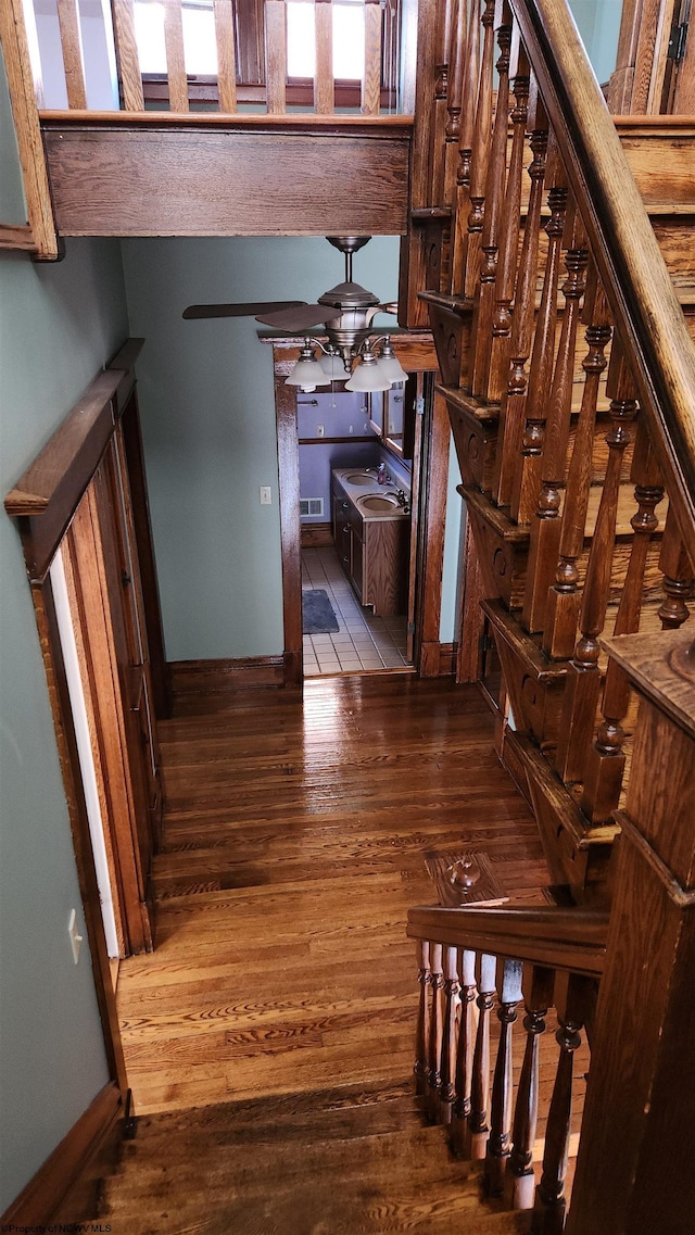 stairs with ceiling fan, wood finished floors, visible vents, and baseboards