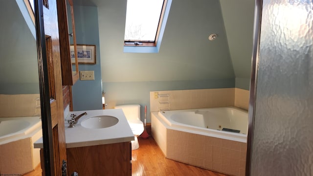 full bath featuring a tub with jets, a skylight, wood finished floors, and vanity