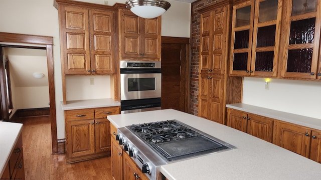 kitchen featuring brown cabinets, light wood-type flooring, stainless steel appliances, and light countertops