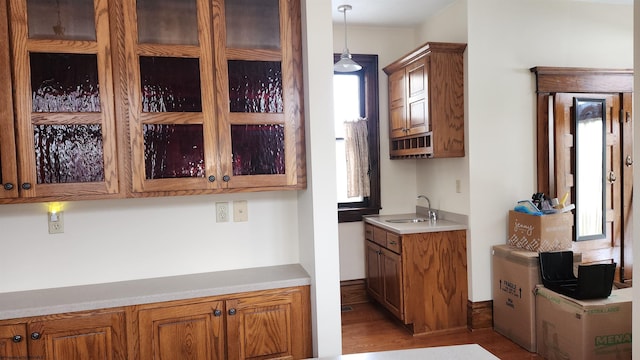 kitchen featuring light countertops, brown cabinets, a sink, and hanging light fixtures