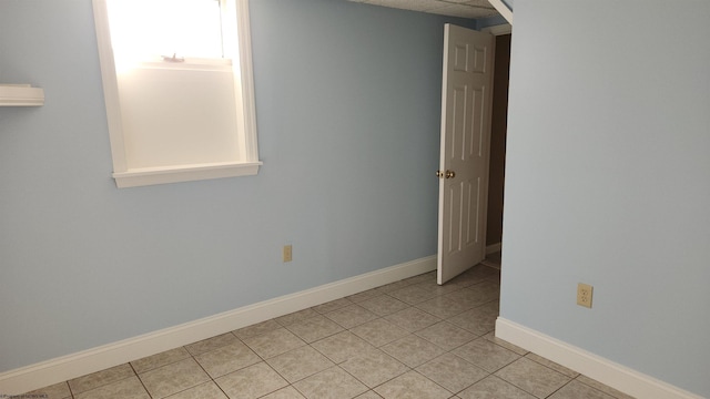 spare room featuring light tile patterned flooring and baseboards