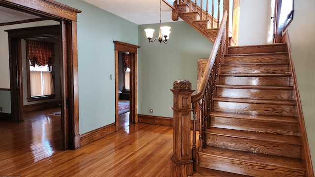 stairs featuring a notable chandelier, wood finished floors, and baseboards