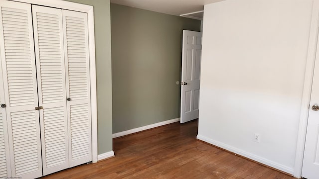 unfurnished bedroom featuring a closet, wood finished floors, and baseboards