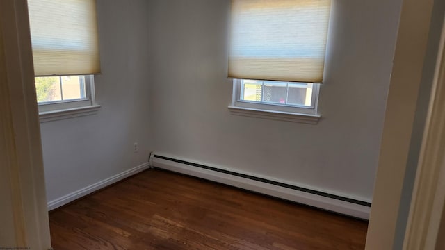 spare room with baseboards, baseboard heating, and dark wood-style flooring