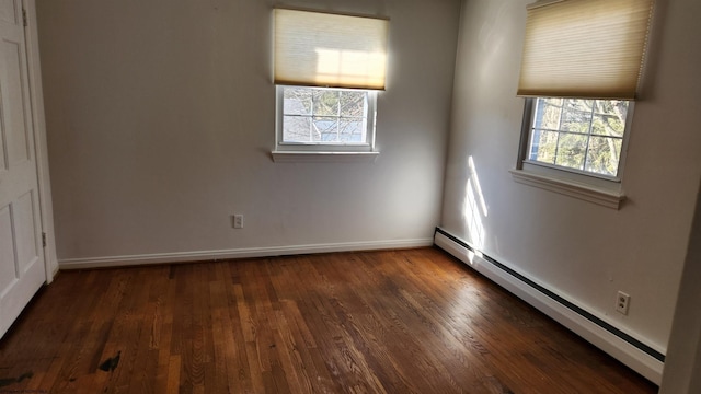 empty room featuring a baseboard radiator, baseboards, and wood finished floors