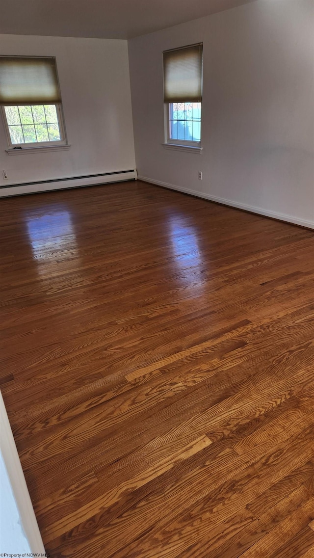 unfurnished room with dark wood-style floors, baseboards, and baseboard heating