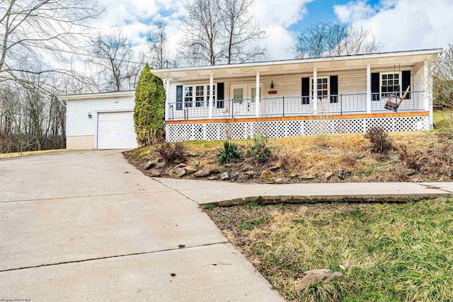 single story home featuring covered porch, concrete driveway, an outbuilding, and a garage