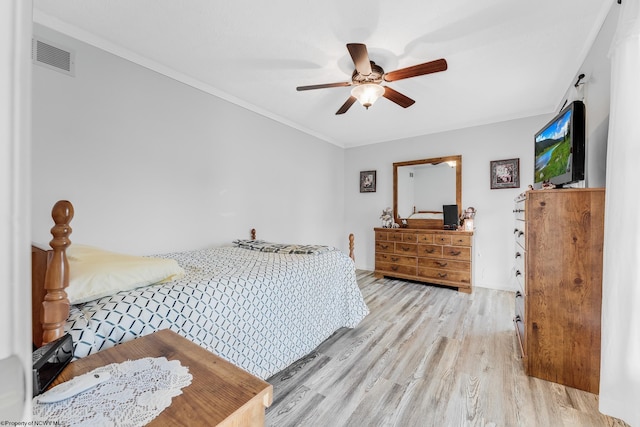 bedroom with a ceiling fan, visible vents, crown molding, and light wood-style flooring