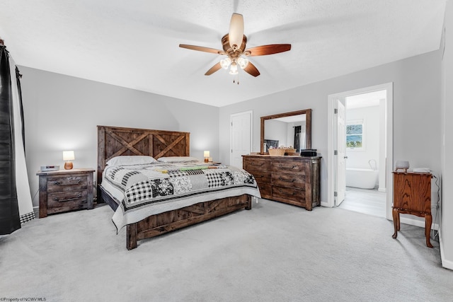 carpeted bedroom with ensuite bathroom, a textured ceiling, a ceiling fan, and baseboards