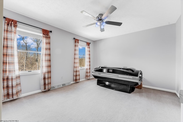 carpeted bedroom with a textured ceiling, a ceiling fan, visible vents, and baseboards