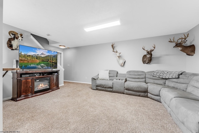 living room featuring carpet, a glass covered fireplace, and baseboards