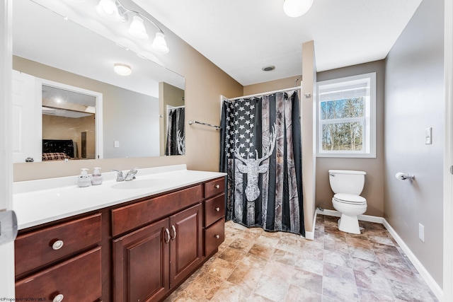 bathroom with baseboards, vanity, and toilet