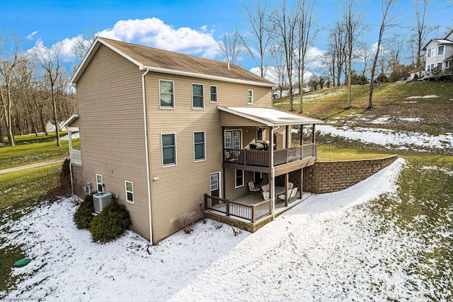 snow covered house with cooling unit and a wooden deck