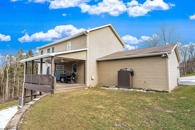 rear view of property with ceiling fan, a yard, and a sunroom