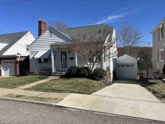 view of front of house with driveway, a shingled roof, a chimney, a detached garage, and an outdoor structure