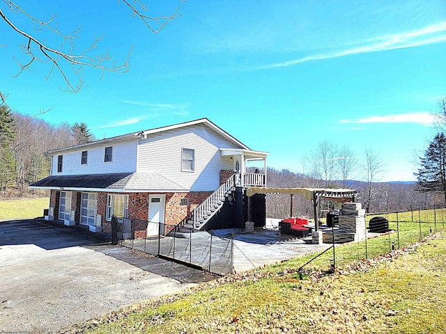 view of front of home featuring a patio, stairway, fence, a front lawn, and brick siding