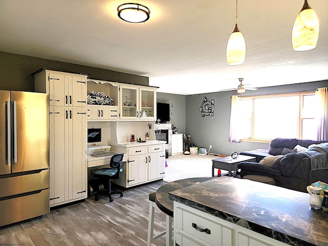 kitchen with dark wood finished floors, a ceiling fan, freestanding refrigerator, glass insert cabinets, and white cabinetry