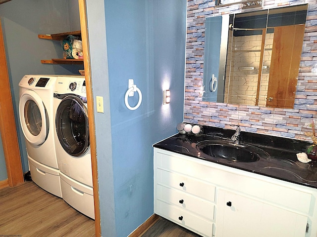 laundry area featuring laundry area, separate washer and dryer, wood finished floors, a sink, and baseboards