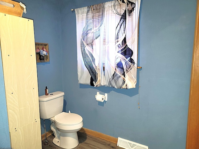 bathroom with toilet, wood finished floors, visible vents, and baseboards