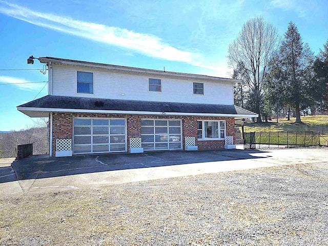 traditional home featuring brick siding, driveway, an attached garage, and fence