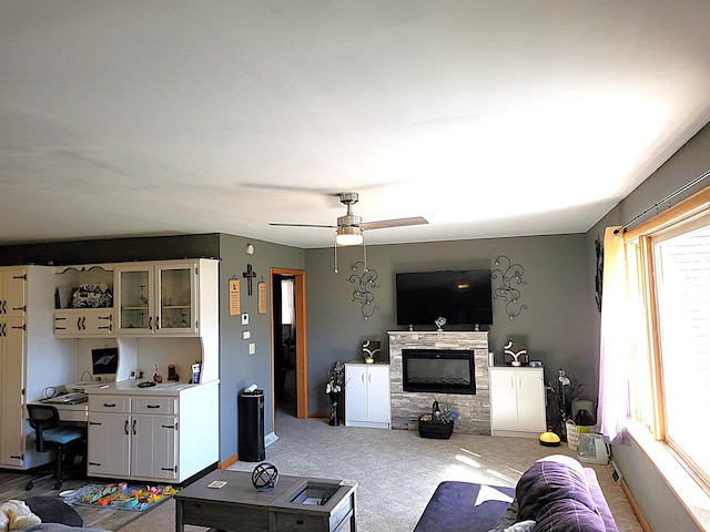 living area featuring a ceiling fan, carpet flooring, a fireplace, and baseboards