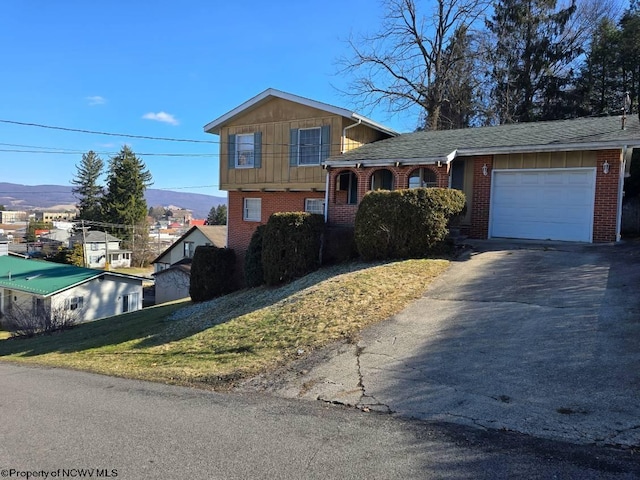 tri-level home featuring driveway, brick siding, and an attached garage