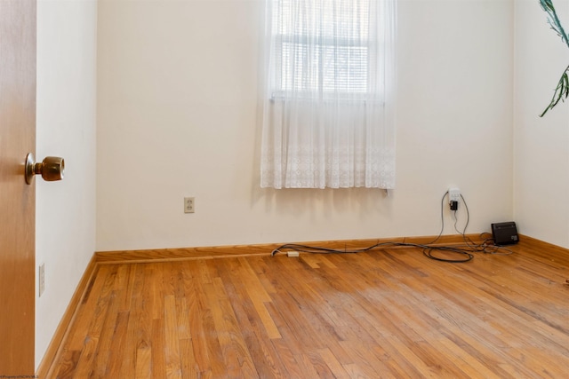 spare room featuring wood-type flooring and baseboards