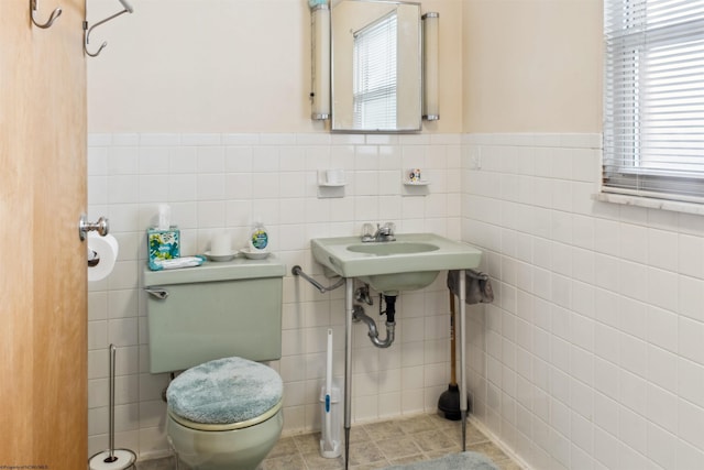 bathroom featuring a wainscoted wall, a healthy amount of sunlight, tile walls, and toilet