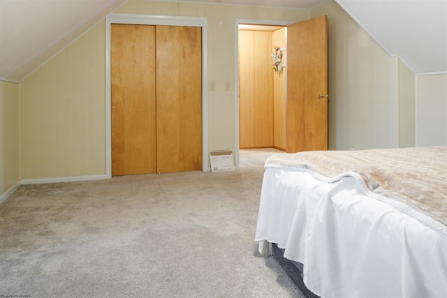 bedroom featuring lofted ceiling, baseboards, a closet, and light colored carpet