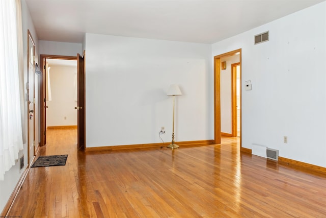 empty room featuring light wood-type flooring, visible vents, and baseboards