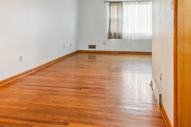 unfurnished room with wood finished floors, visible vents, and baseboards