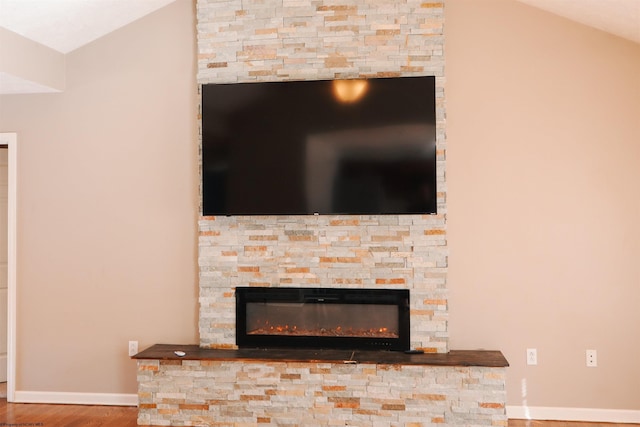 interior details featuring a stone fireplace, wood finished floors, and baseboards