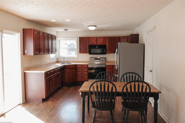 kitchen featuring a textured ceiling, wood finished floors, a sink, light countertops, and appliances with stainless steel finishes