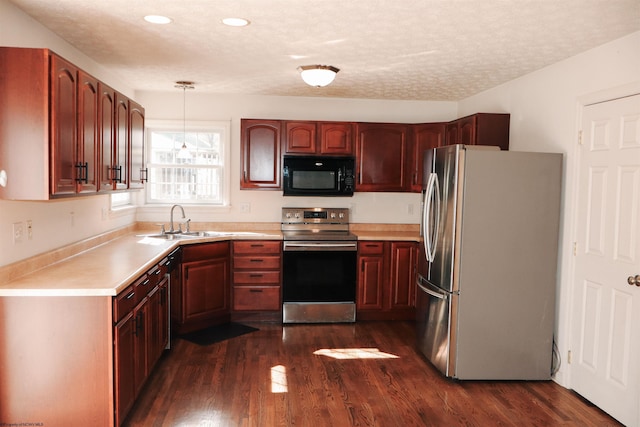 kitchen with dark wood-style floors, stainless steel appliances, a textured ceiling, light countertops, and a sink