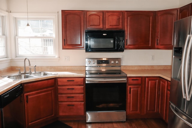 kitchen featuring dark brown cabinets, stainless steel appliances, a sink, and light countertops