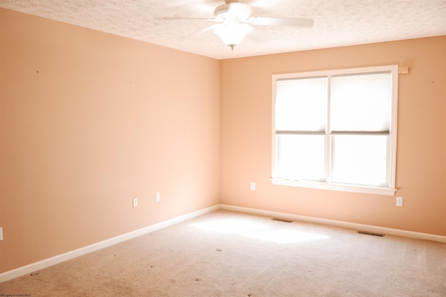 carpeted spare room with a textured ceiling, visible vents, and baseboards