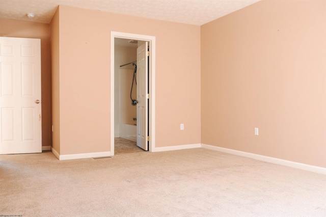 unfurnished bedroom featuring baseboards, a textured ceiling, and light colored carpet