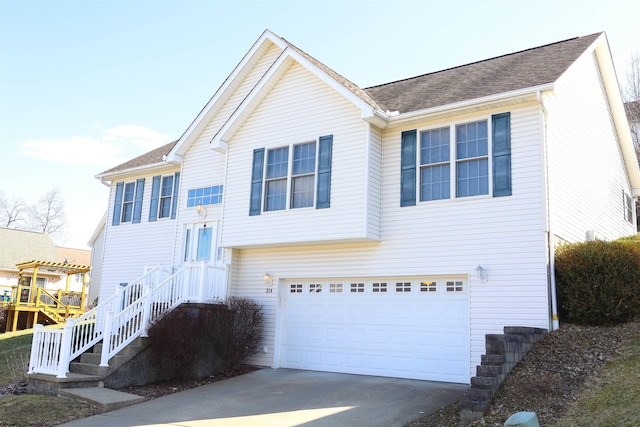 raised ranch with a garage, a shingled roof, and concrete driveway