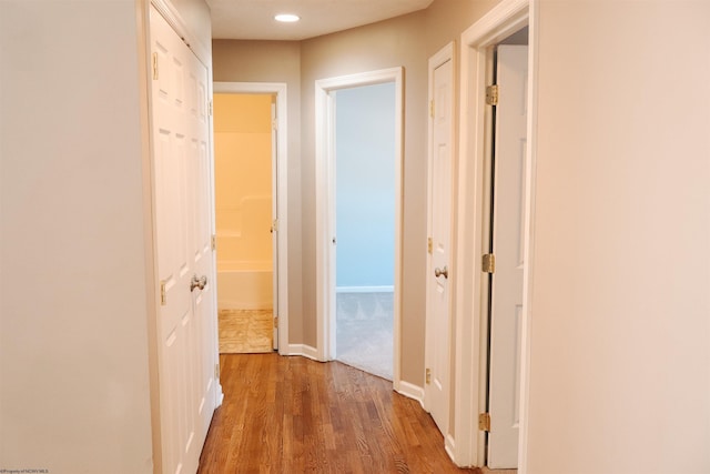 corridor with recessed lighting, wood finished floors, and baseboards