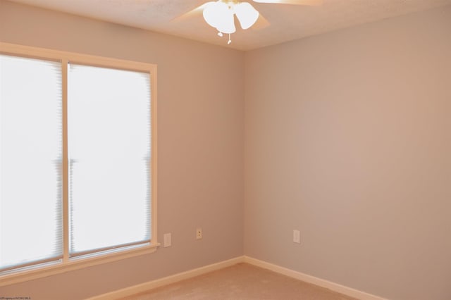 spare room featuring light carpet, ceiling fan, a textured ceiling, and baseboards