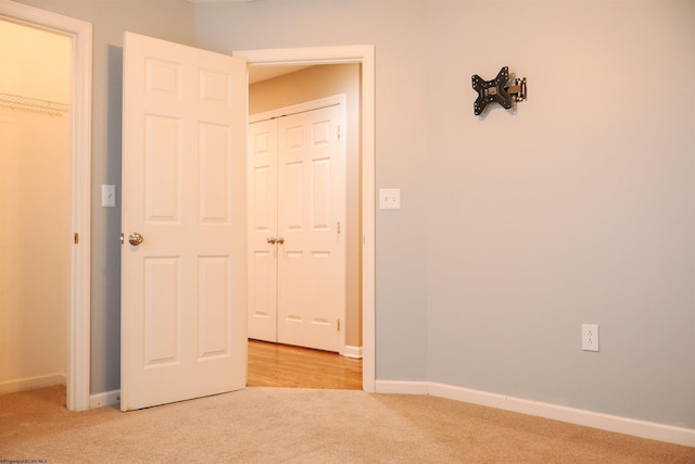 unfurnished bedroom with light carpet, baseboards, and a closet