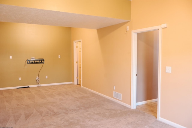 carpeted spare room with visible vents and baseboards