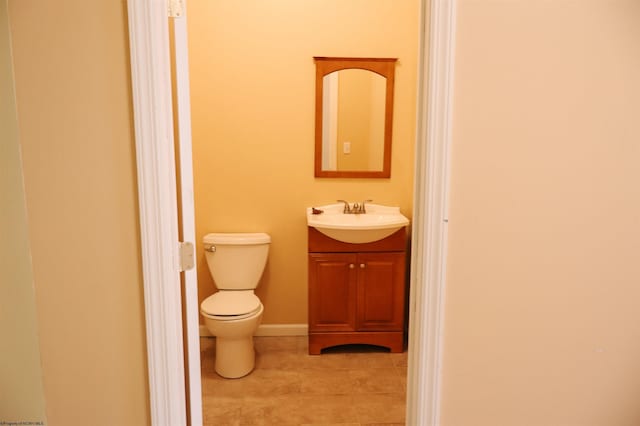 half bath featuring toilet, tile patterned floors, baseboards, and vanity